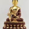 Front view of an 18.5-inch Tibetan Medicine Buddha sculpture seated in full lotus posture, holding a myrobalan plant and medicine bowl, with a hand-painted gold face, fire-gilded 24K gold body, deep red-brown robes and a two-tone double lotus throne.
